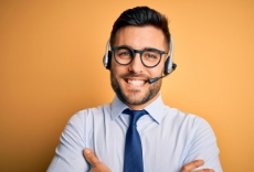 A person with a light blue shirt crossing their arms while wearing a headset