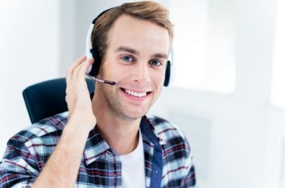 A person smiling while tapping their headset