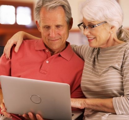 Two elderly people looking at a laptop