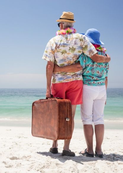 Two elderly people stood on a sunny beach
